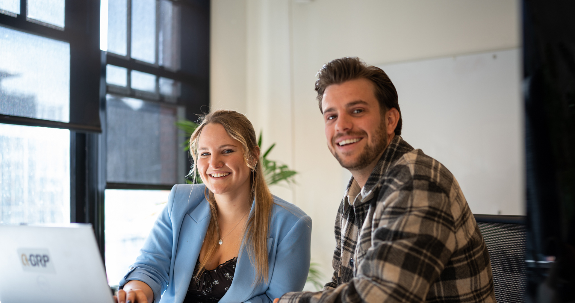 Aline and Nick behind their desk for candidates banner