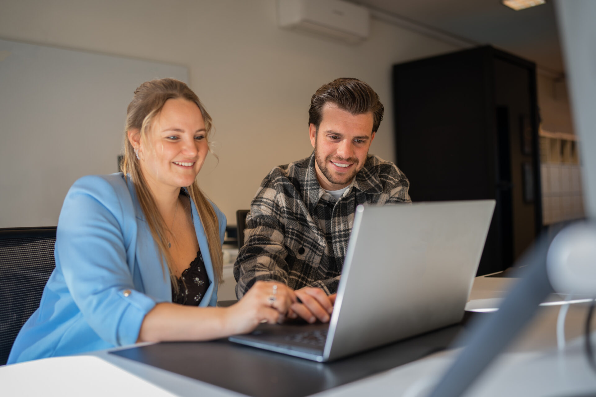 Aline and Nick working behind their laptop sales outsourcing banner